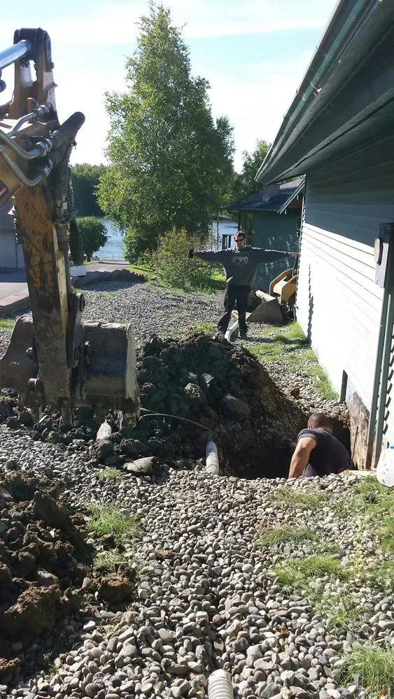 A man is digging a hole in the ground in front of a house.