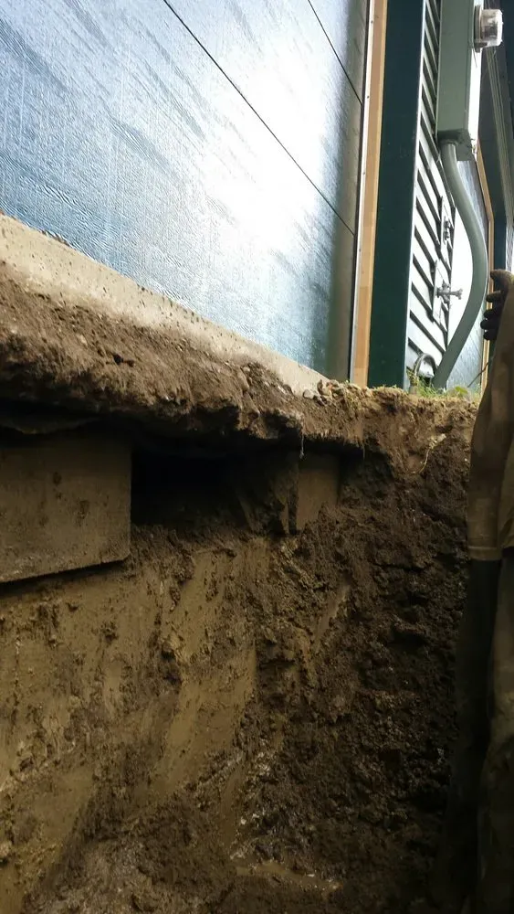 A person is digging a hole in the ground next to a house.