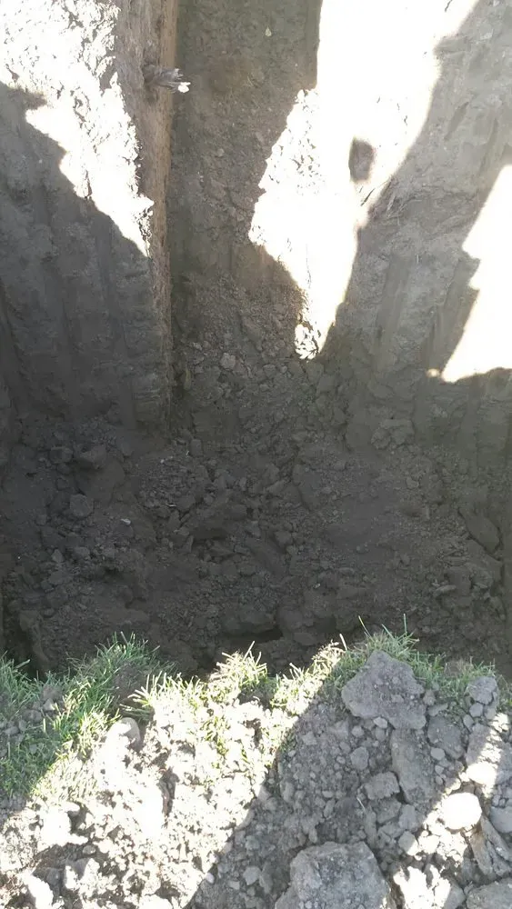 A person is digging a hole in the ground with a shovel.