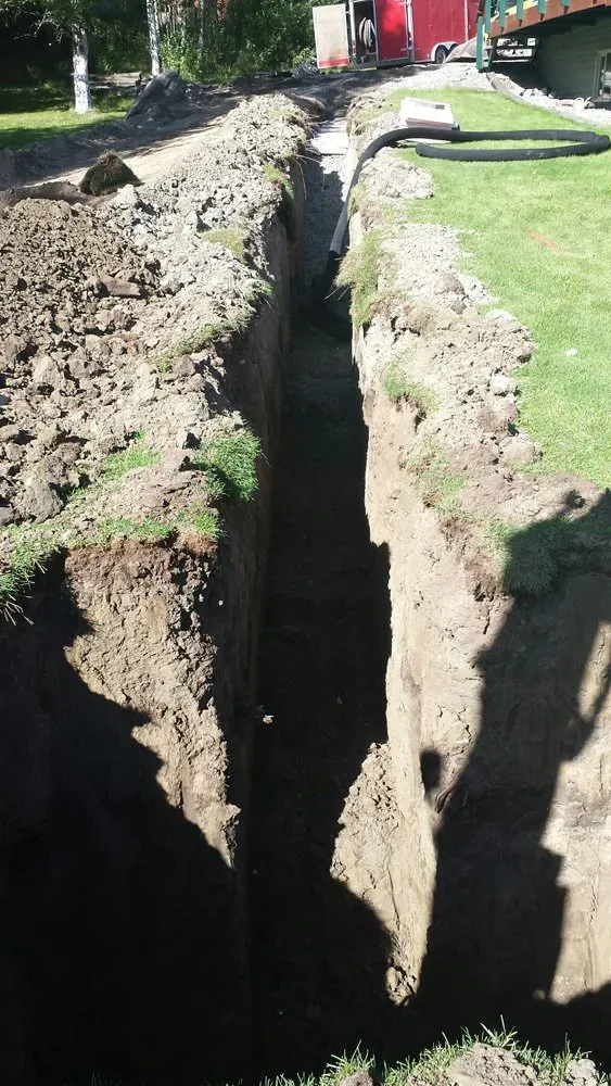 A large hole in the ground is being dug in a yard.