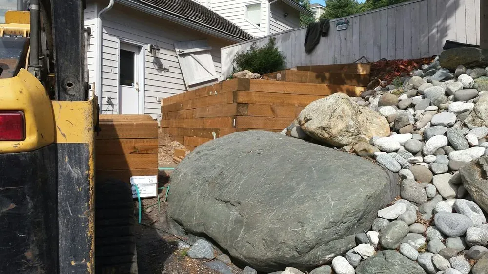 A large rock is sitting on top of a pile of rocks in front of a house.