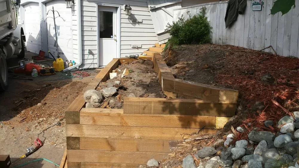 A wooden fence is being built in front of a white house.