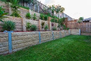 A backyard with a stone retaining wall and a wooden fence.