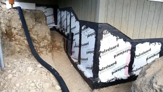 A drainage system is being installed on the side of a house