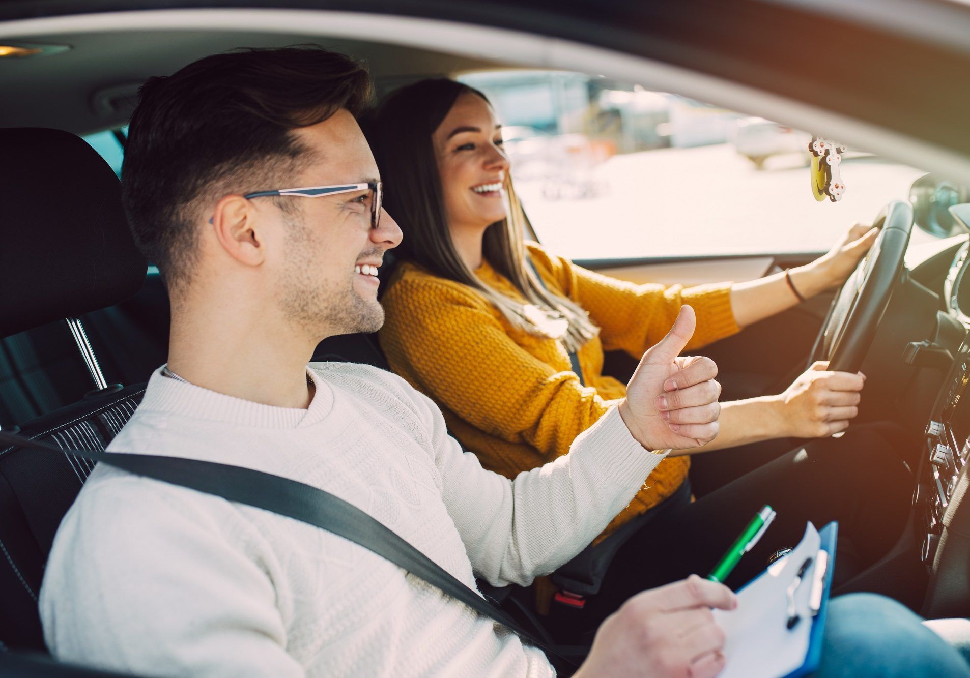 Un homme et une femme sont assis dans une voiture et lèvent le pouce.