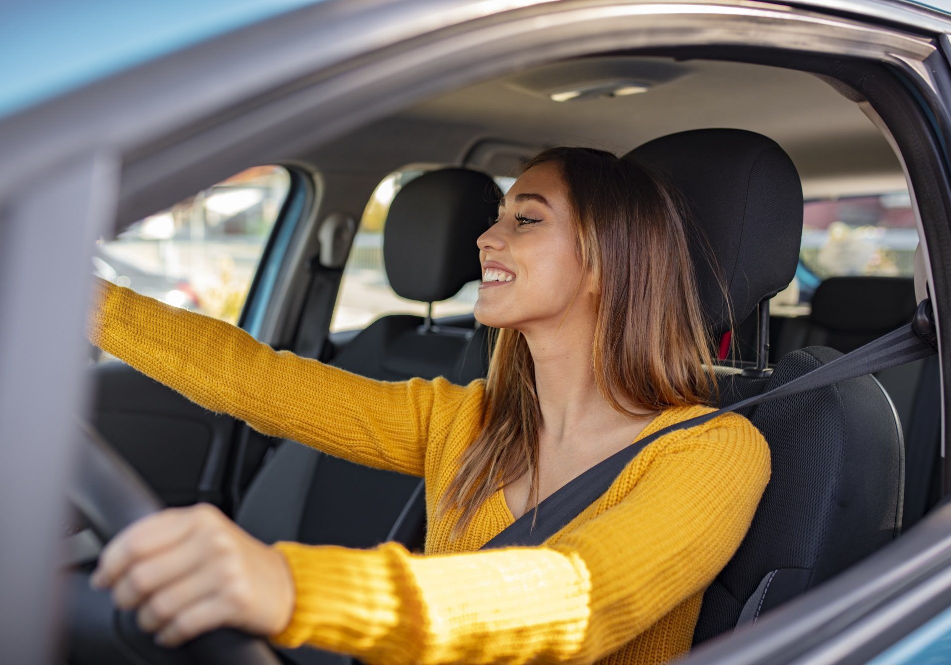 Une femme en pull jaune conduit une voiture.