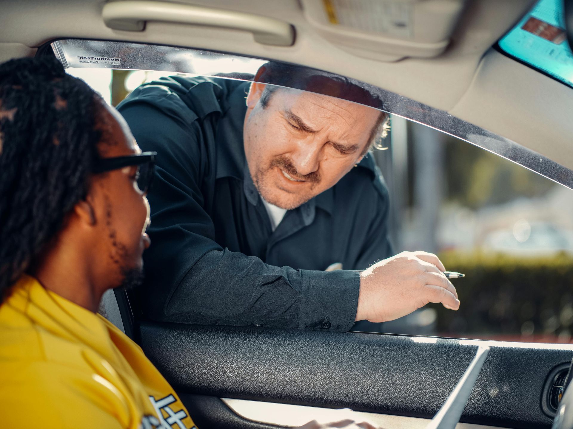 Un homme parle à un autre homme dans une voiture.