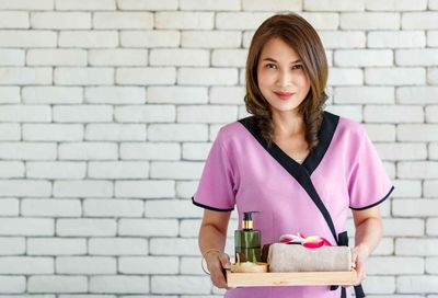 Asian Massage Therapist Holding Massage Oils and Towels