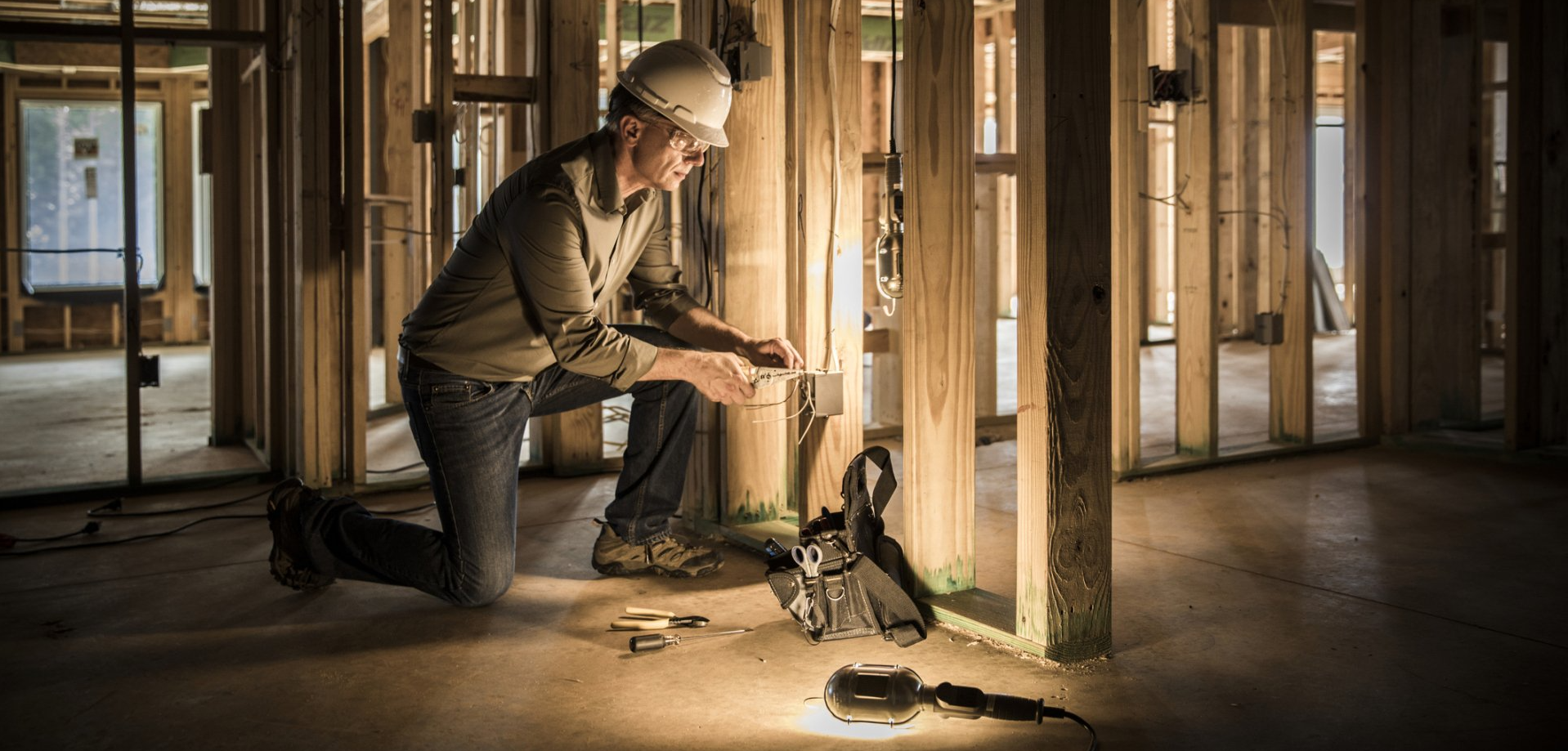 Electrician installing electrical components in framed wall stud