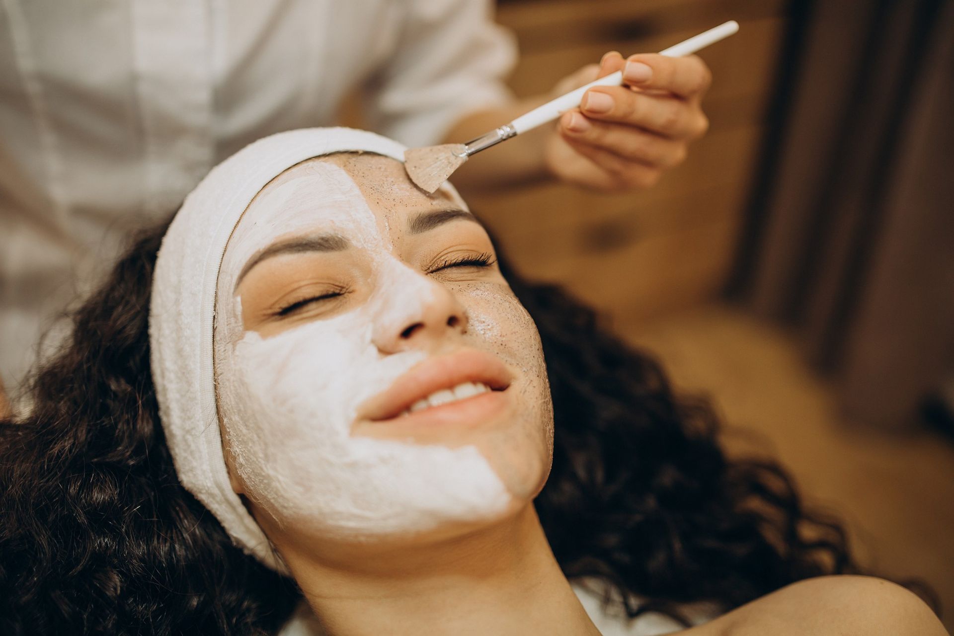 A woman is getting a facial treatment at a beauty salon.
