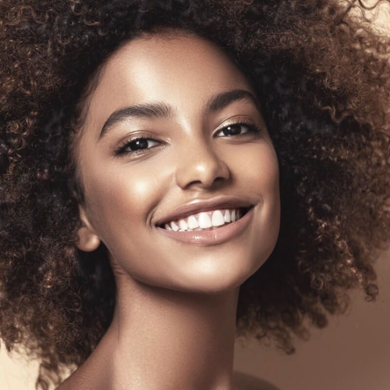 A woman with curly hair is smiling for the camera.