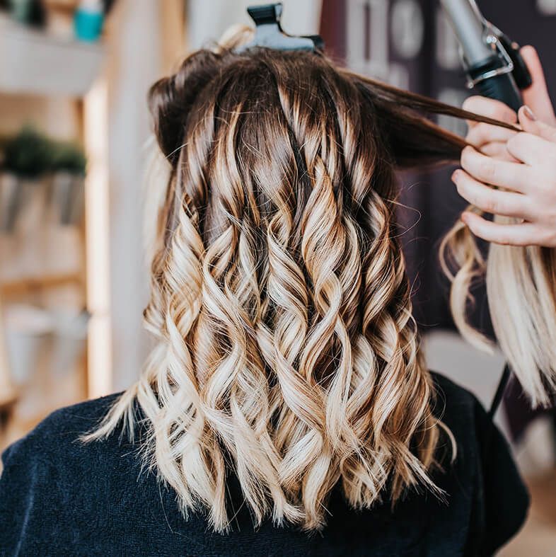A woman is getting her hair curled by a hairdresser.