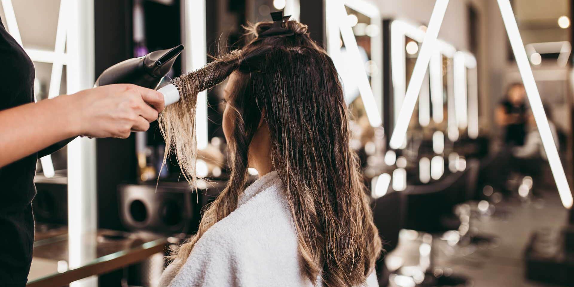 A woman is getting her hair blow dried by a hairdresser in a salon.