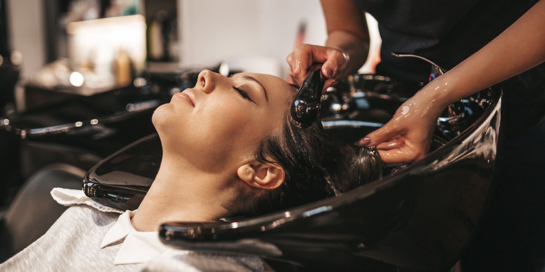 A woman is getting her hair washed at a hair salon.