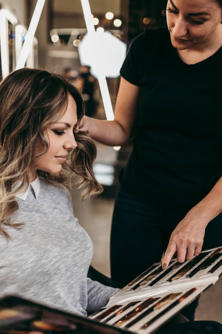 A woman is getting her hair dyed by a hairdresser in a salon.