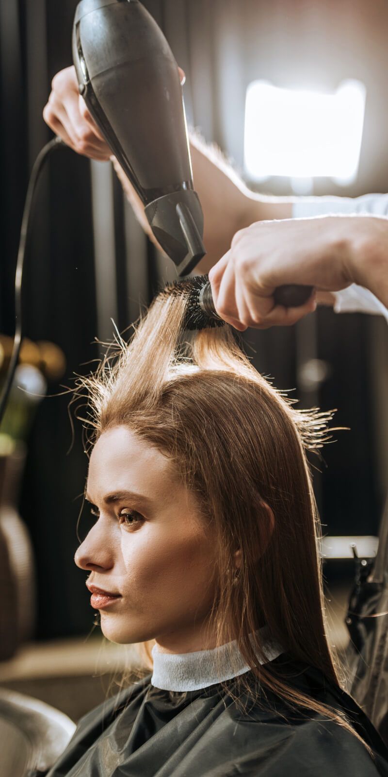 A woman is getting her hair blow dried by a hairdresser in a salon.