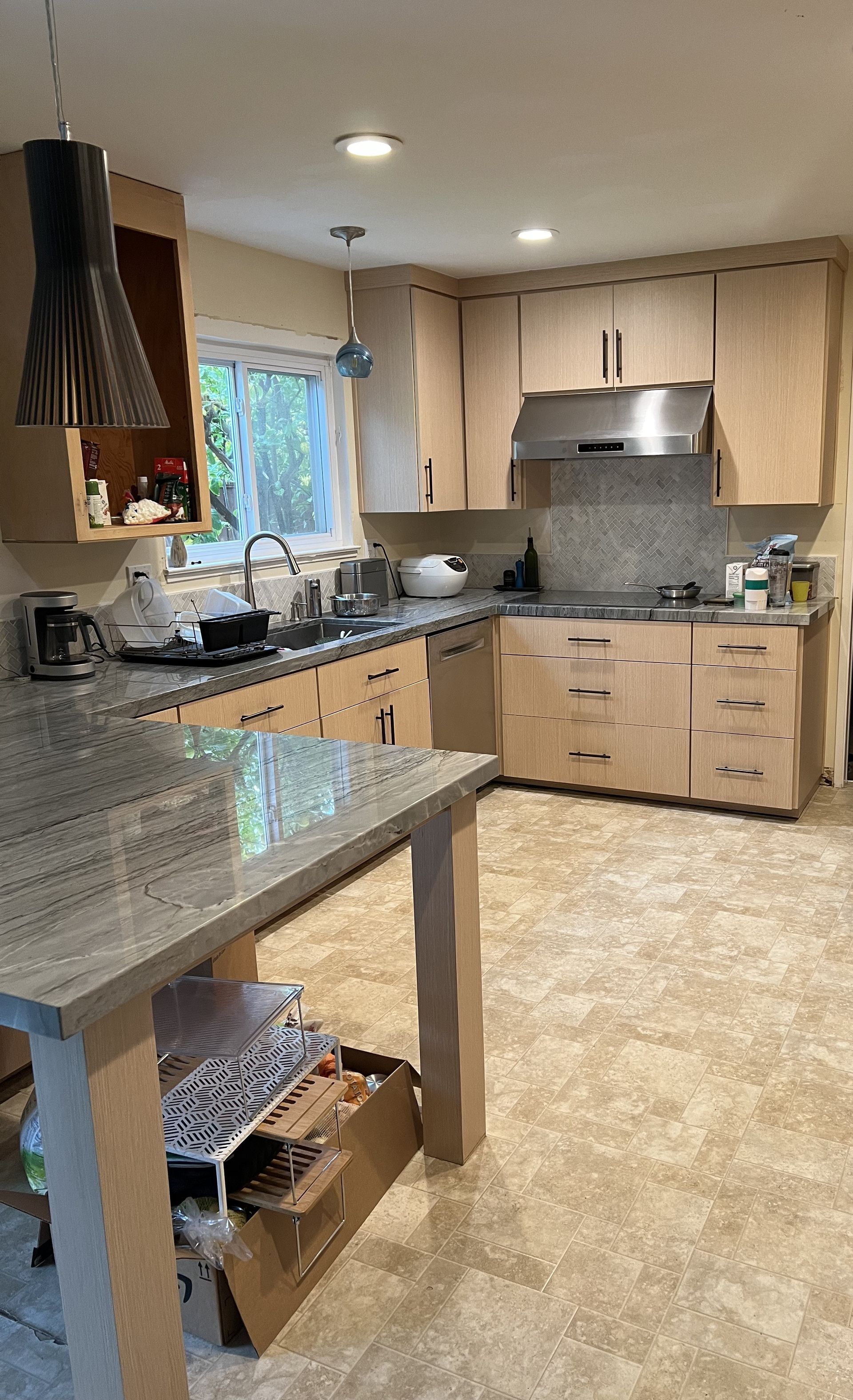 A kitchen with wooden cabinets , granite counter tops , stainless steel appliances and a large window.