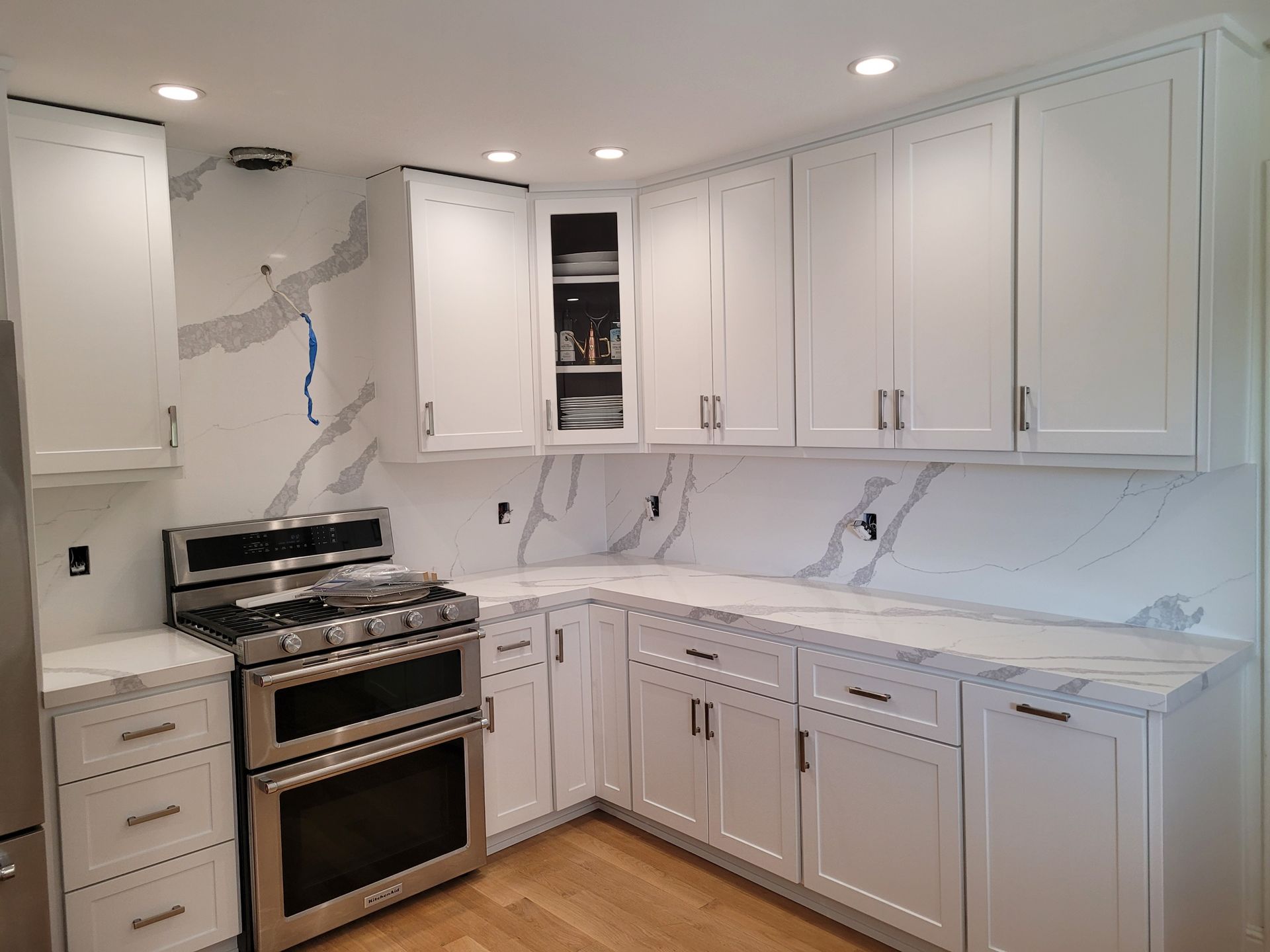 A kitchen with white cabinets , stainless steel appliances , and marble counter tops.