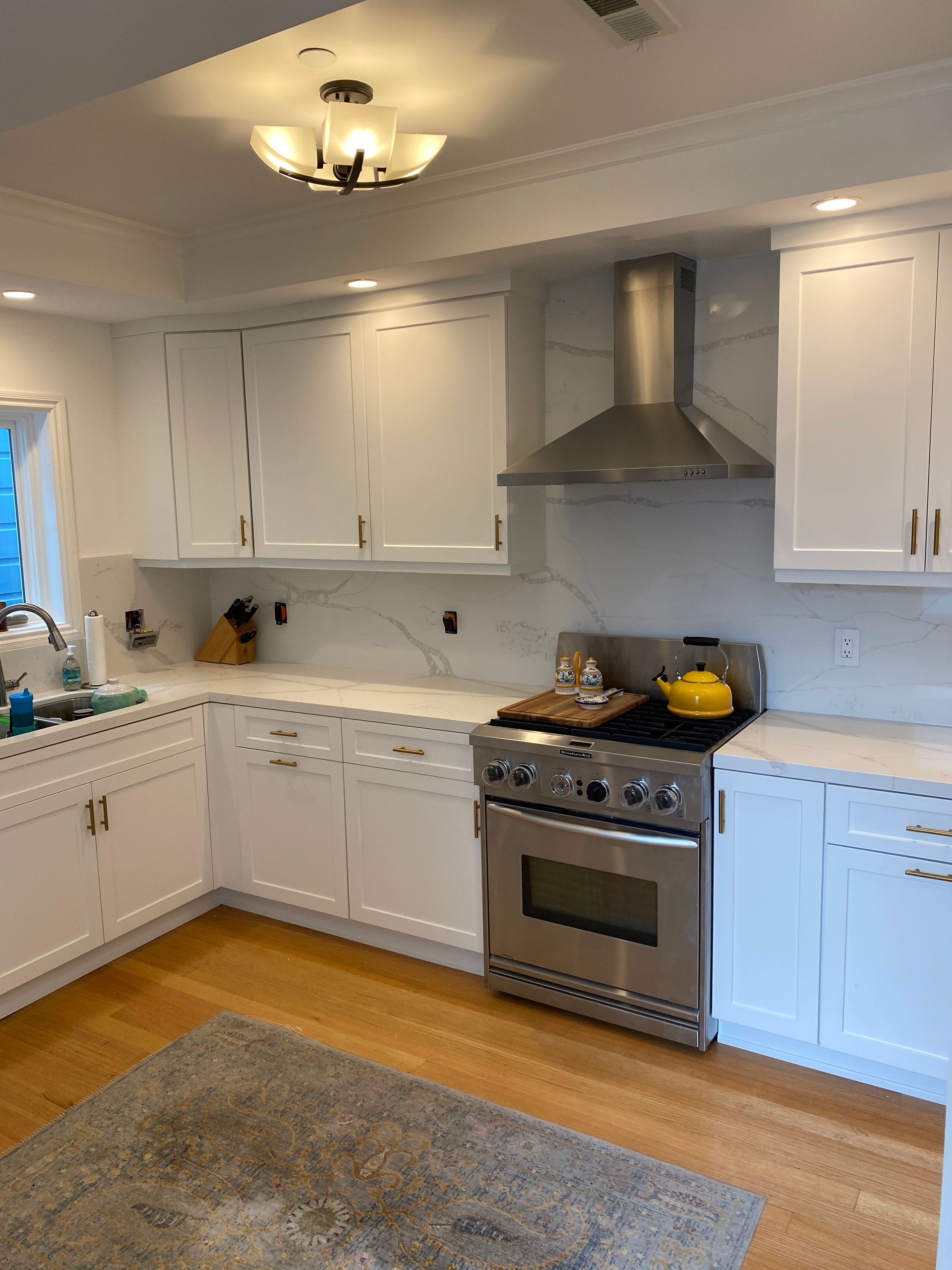 A kitchen with white cabinets , a stove , and a sink.