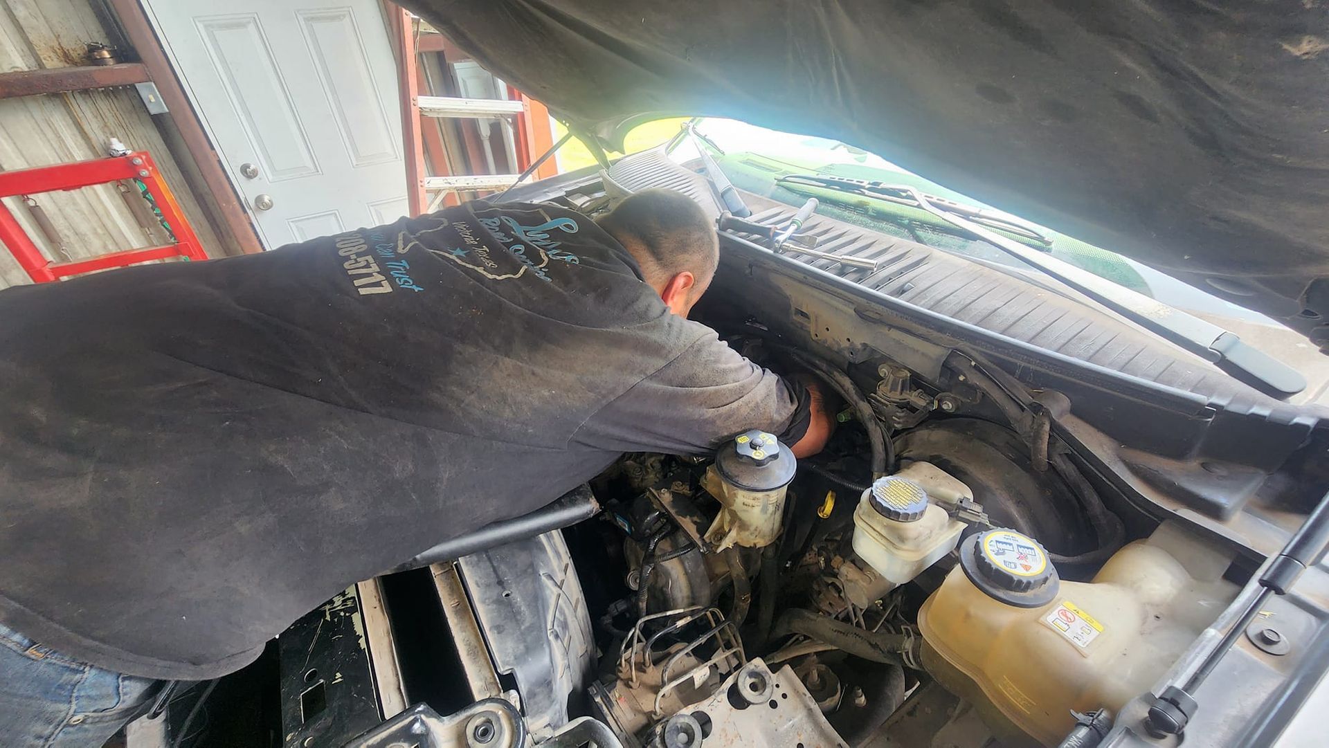 Mechanic working on a car engine under the hood.