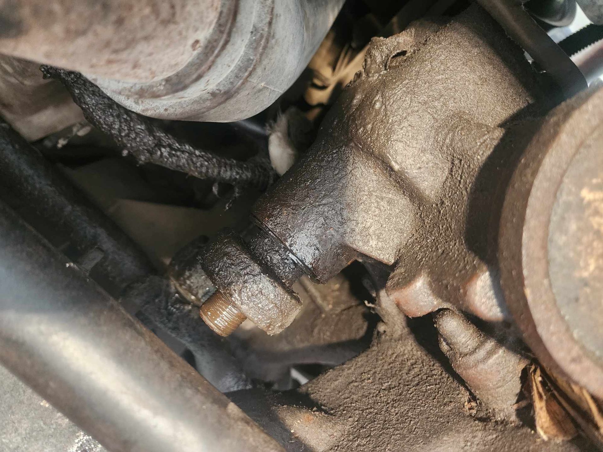 Engine component with oil leak, covered in grime.