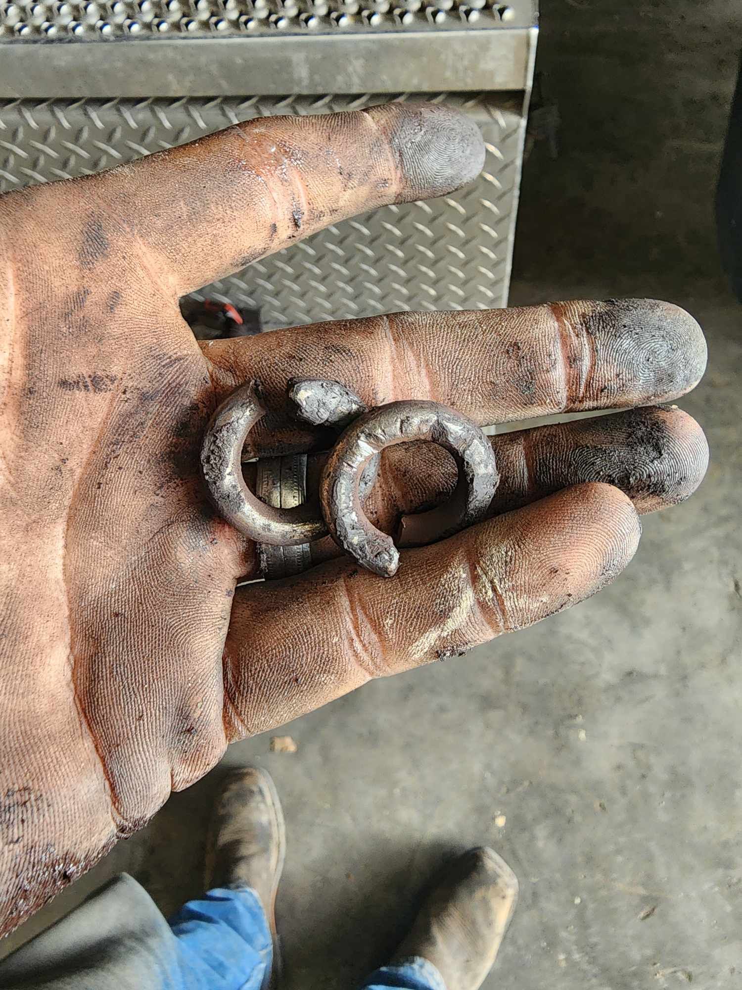 Dirty hand holding two worn metal clips.