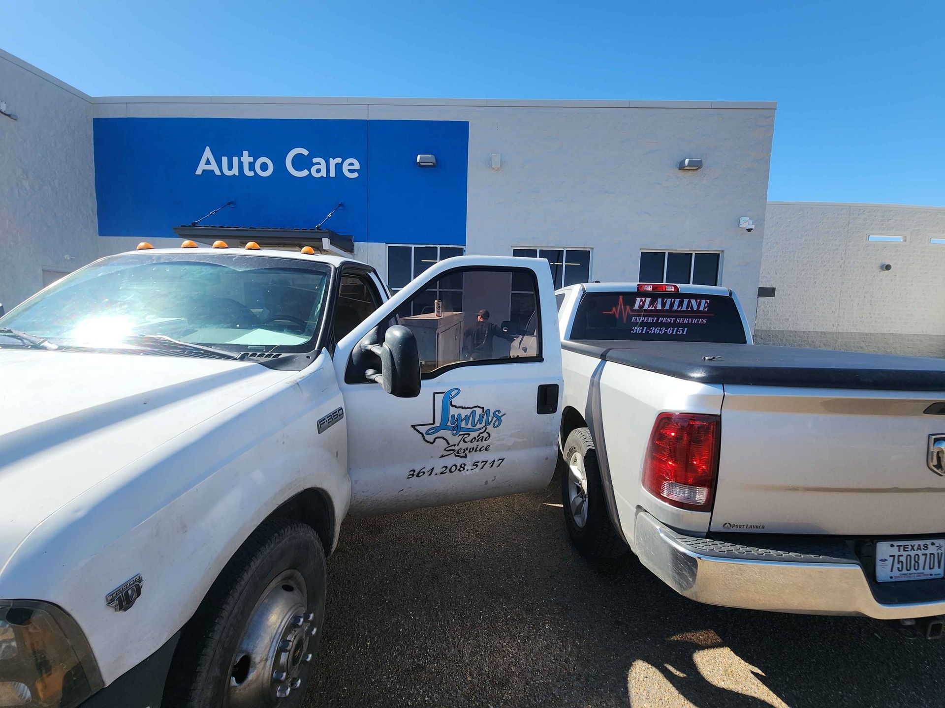Two white trucks parked outside an 