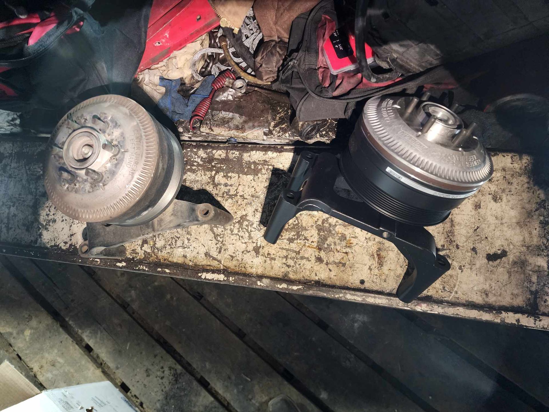 Two metal vehicle parts on a dirty surface, likely a repair or removal context.