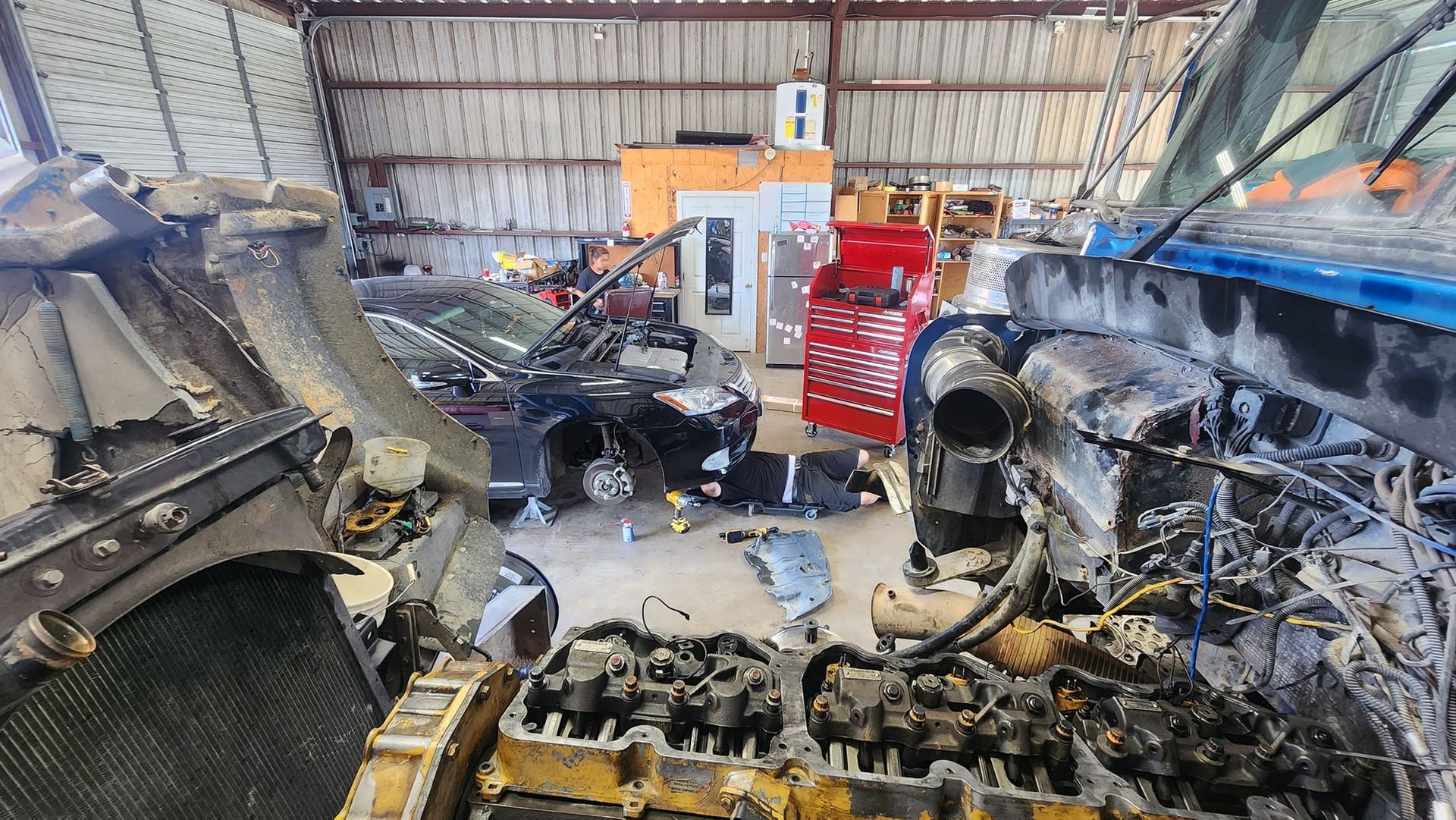Burned-out vehicles inside a cluttered garage; charred metal and debris cover the floor.