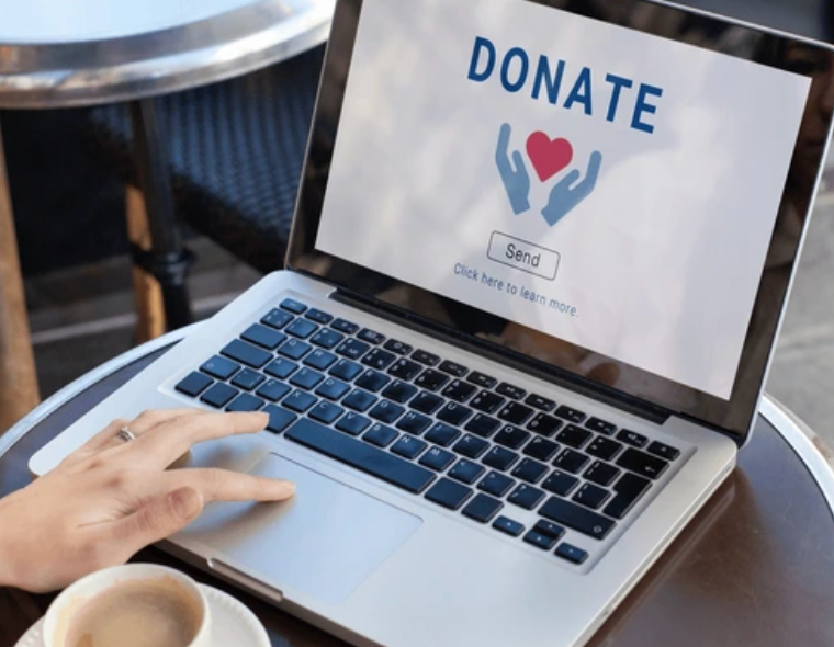 A person is typing on a laptop that says donate on the screen