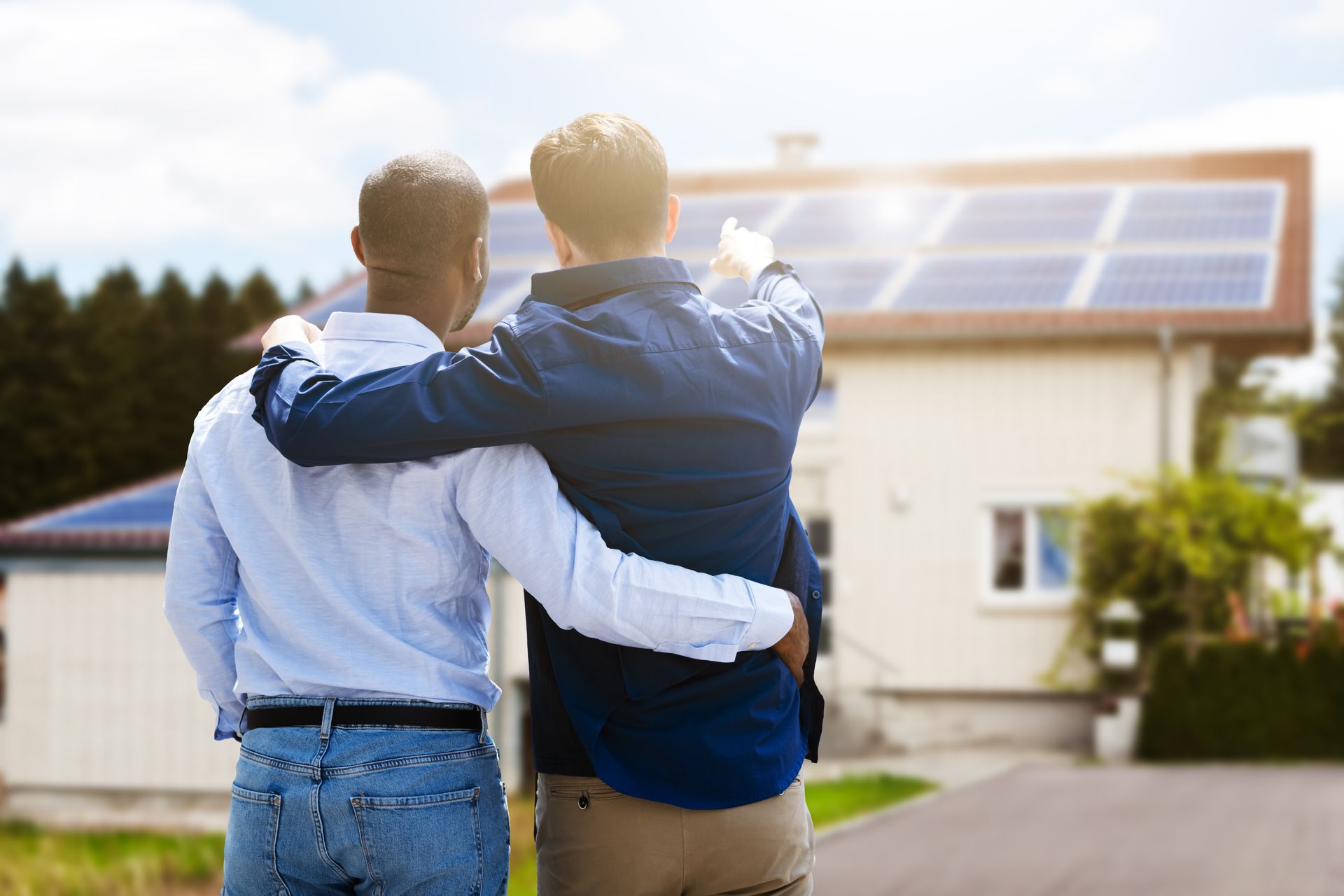 Two men are standing in front of a house with solar panels on the roof.