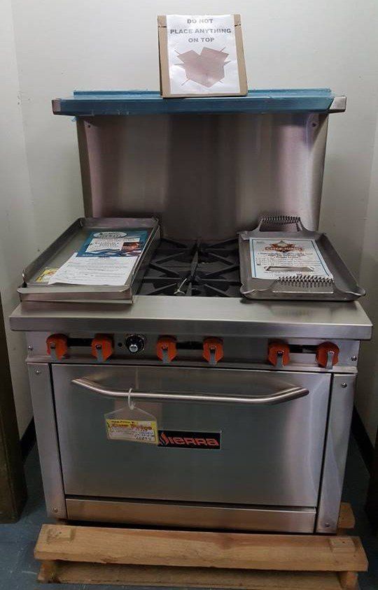 A stainless steel stove and oven are sitting on a wooden pallet.