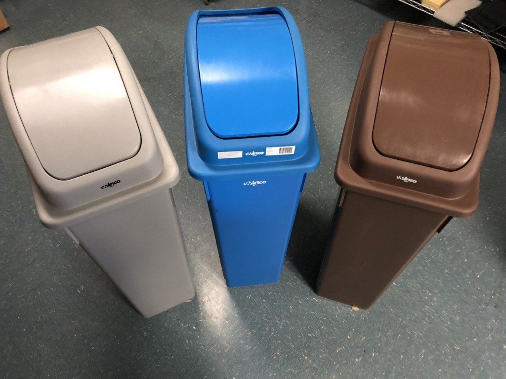 Three trash cans are lined up next to each other on the floor