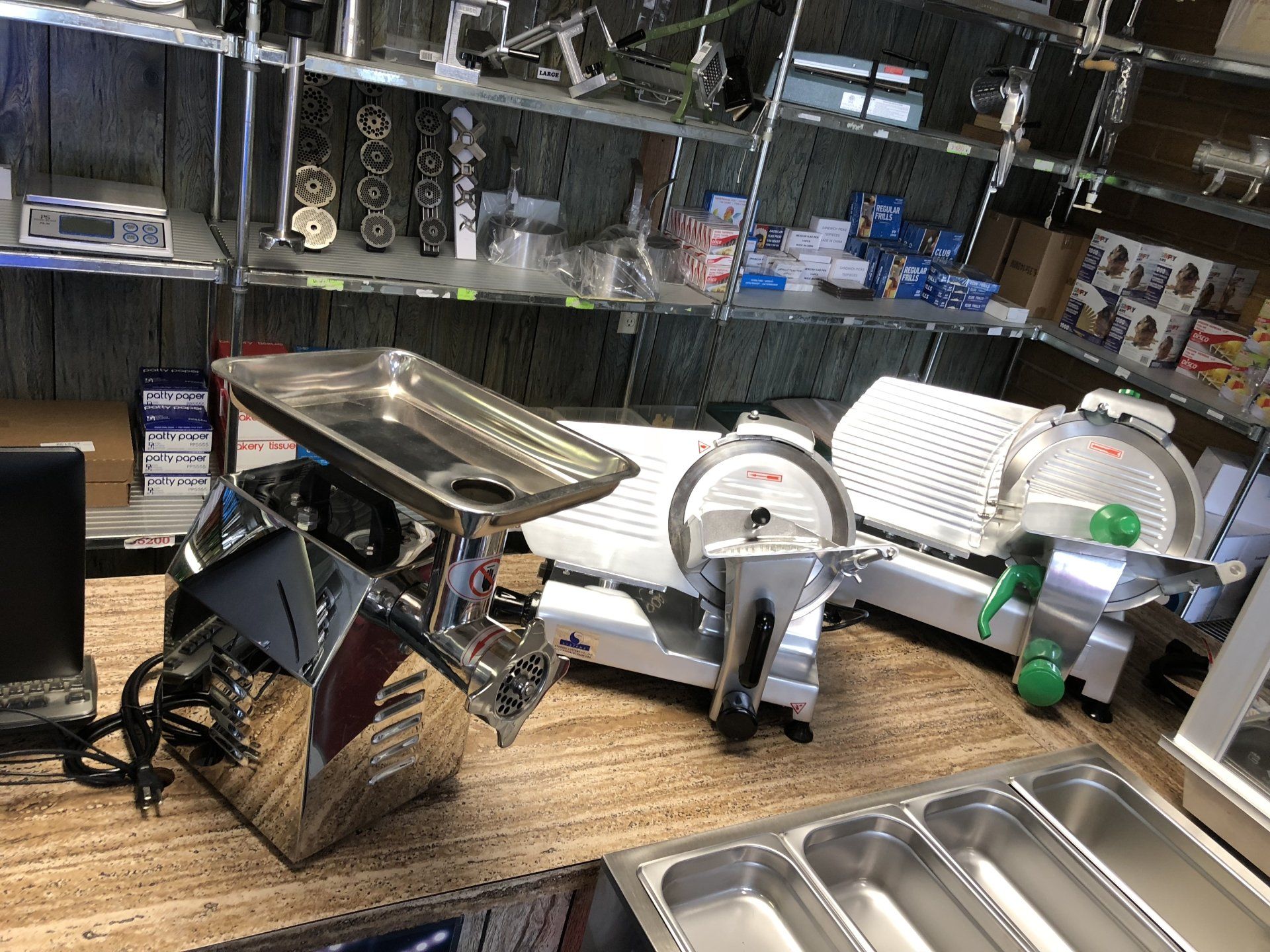 A meat grinder and a meat slicer are sitting on a counter in a store.