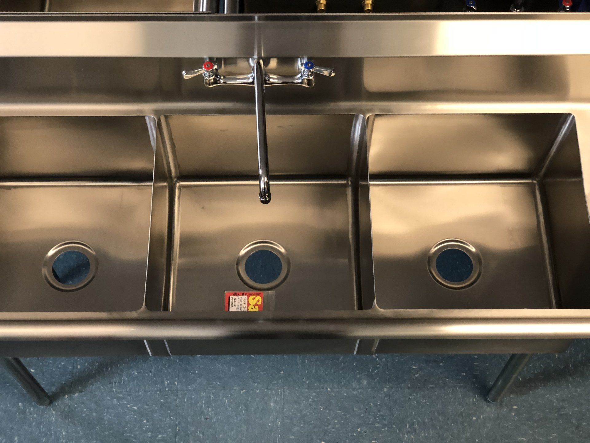 A stainless steel kitchen sink with three sinks and a faucet