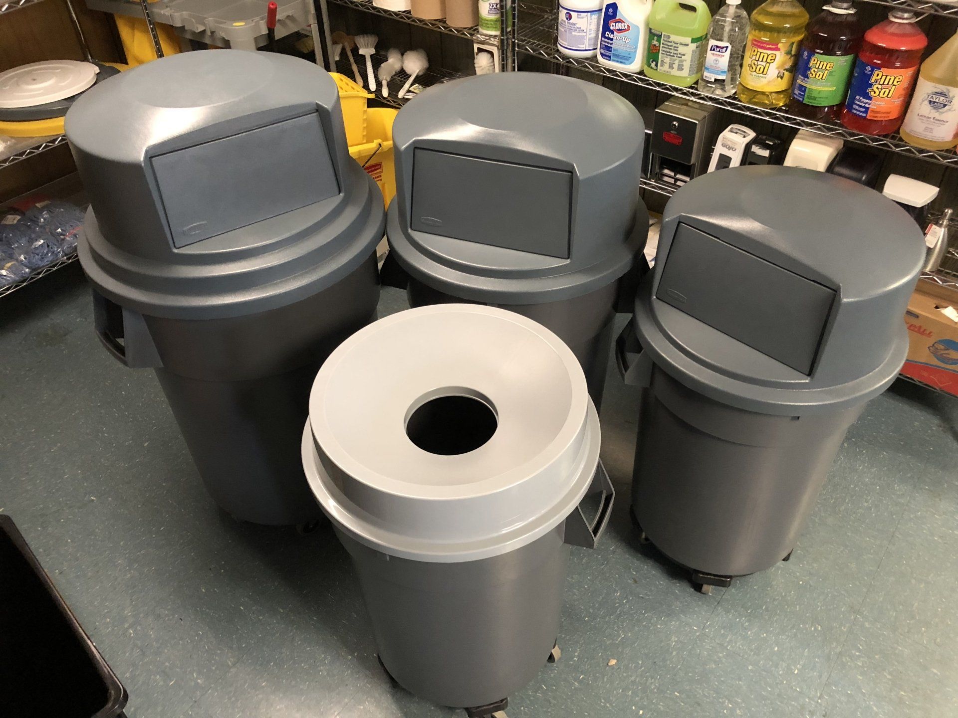 A group of trash cans are sitting on the floor in a room.