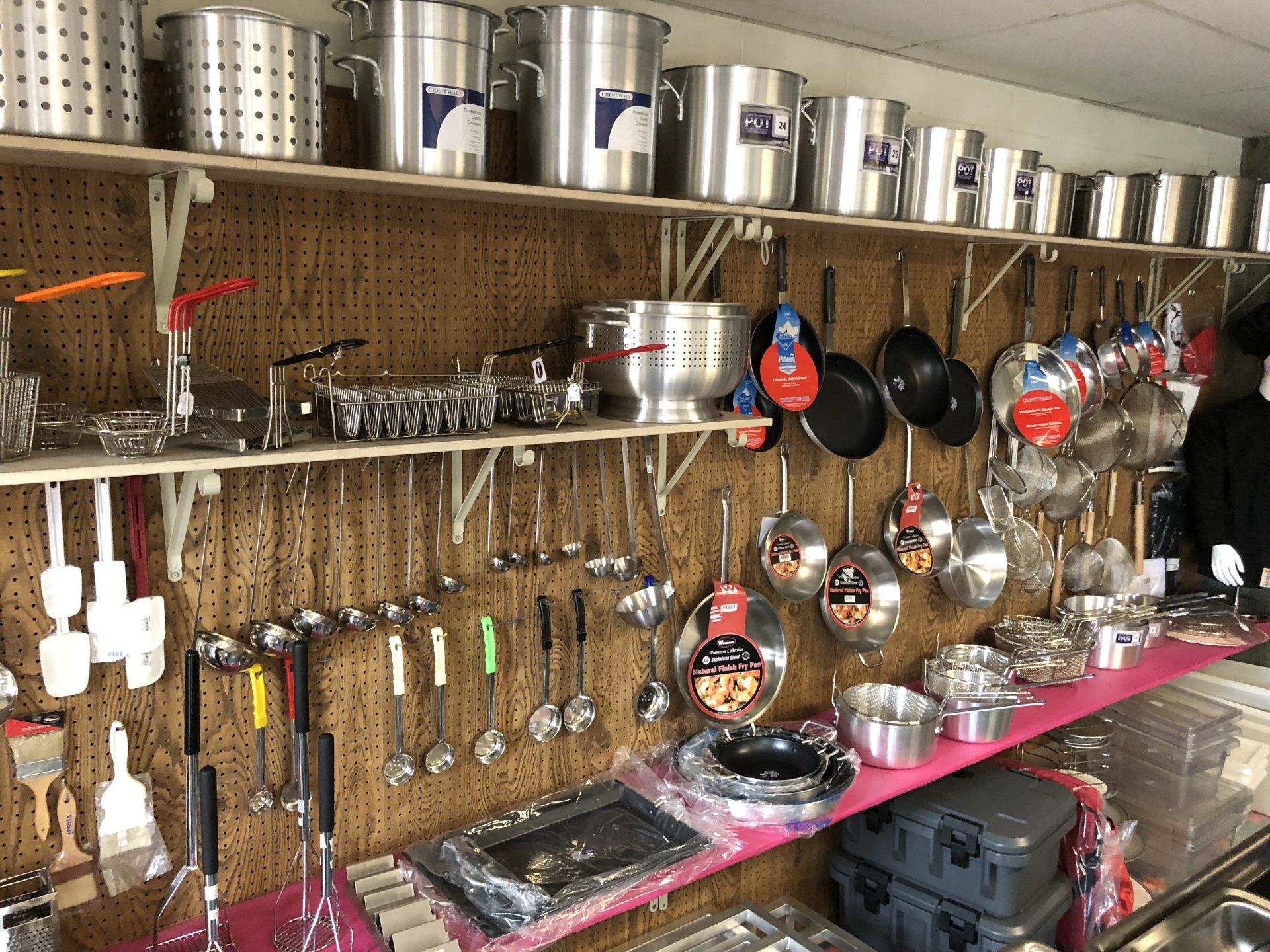 A bunch of pots and pans hanging on a wall in a store