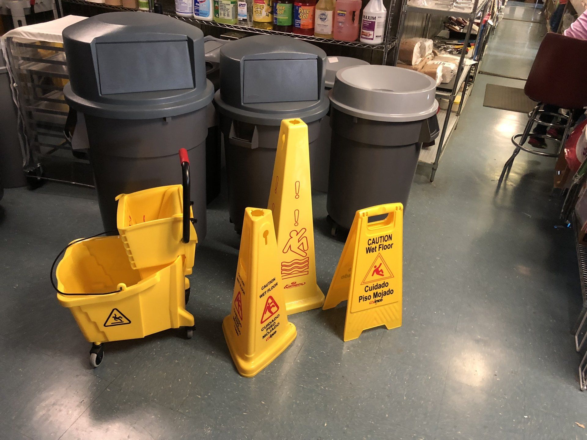 A yellow mop bucket is sitting next to a yellow caution sign