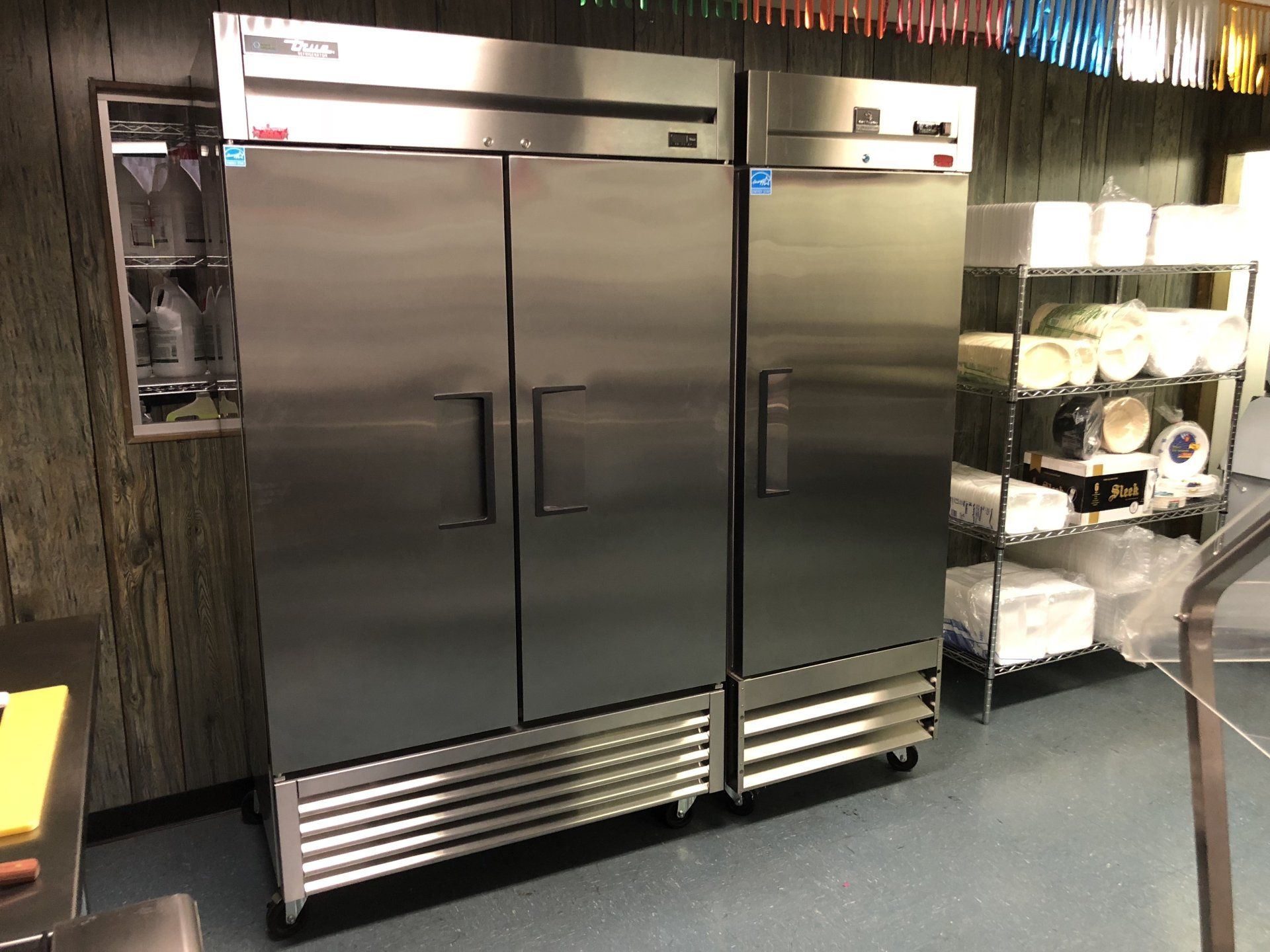 Two stainless steel refrigerators are sitting next to each other in a kitchen.