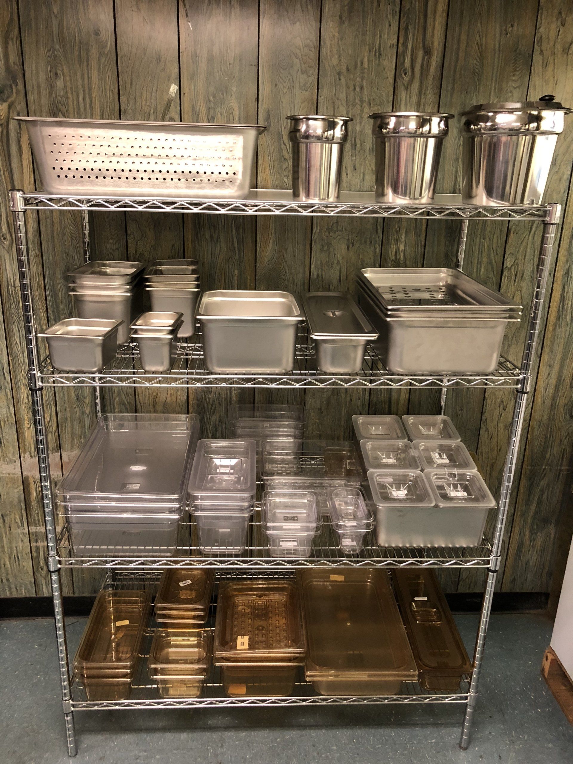 A shelf filled with stainless steel pans and plastic containers.