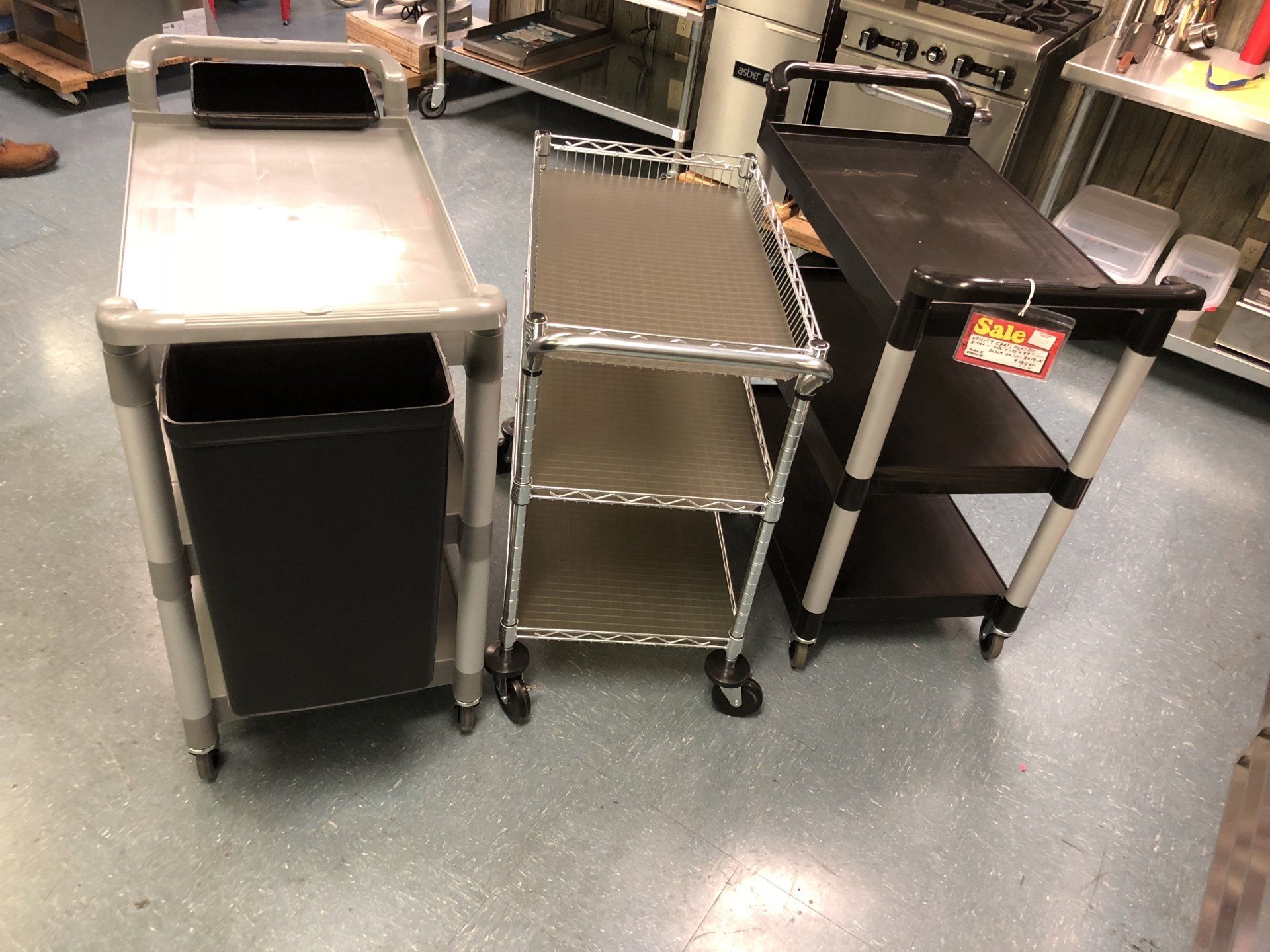 Three carts are sitting on the floor in a kitchen.