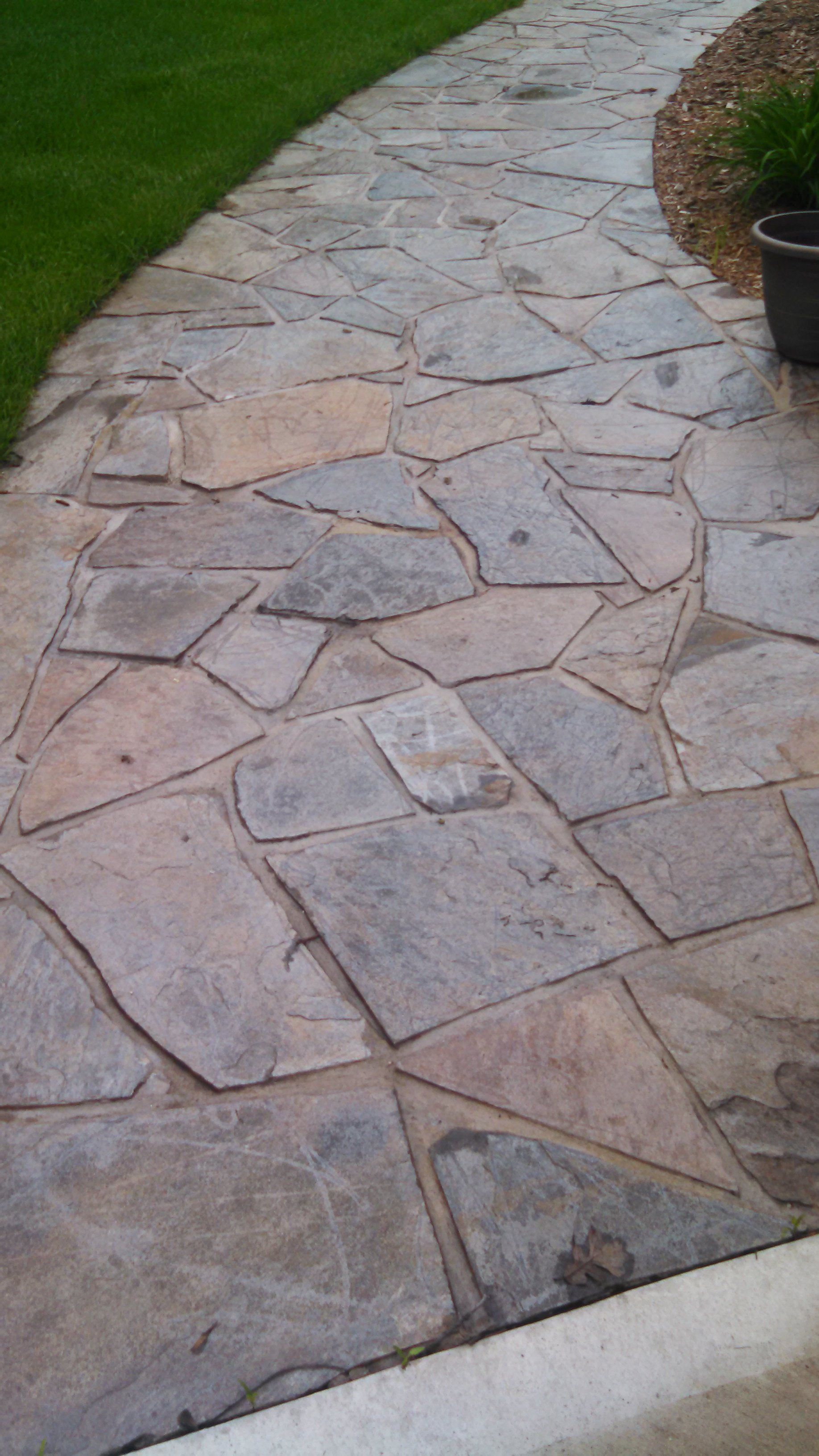 A stone walkway leading to a lush green lawn.