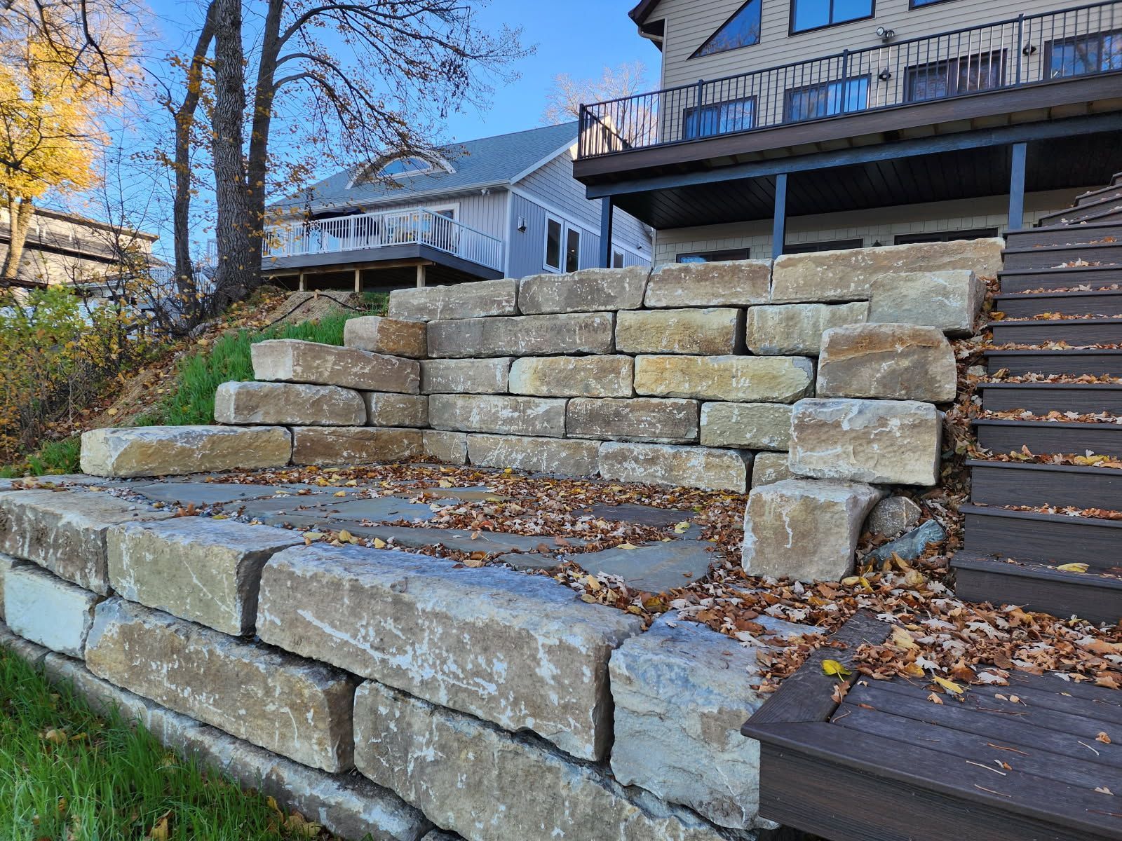 A large stone wall with stairs leading up to a house.
