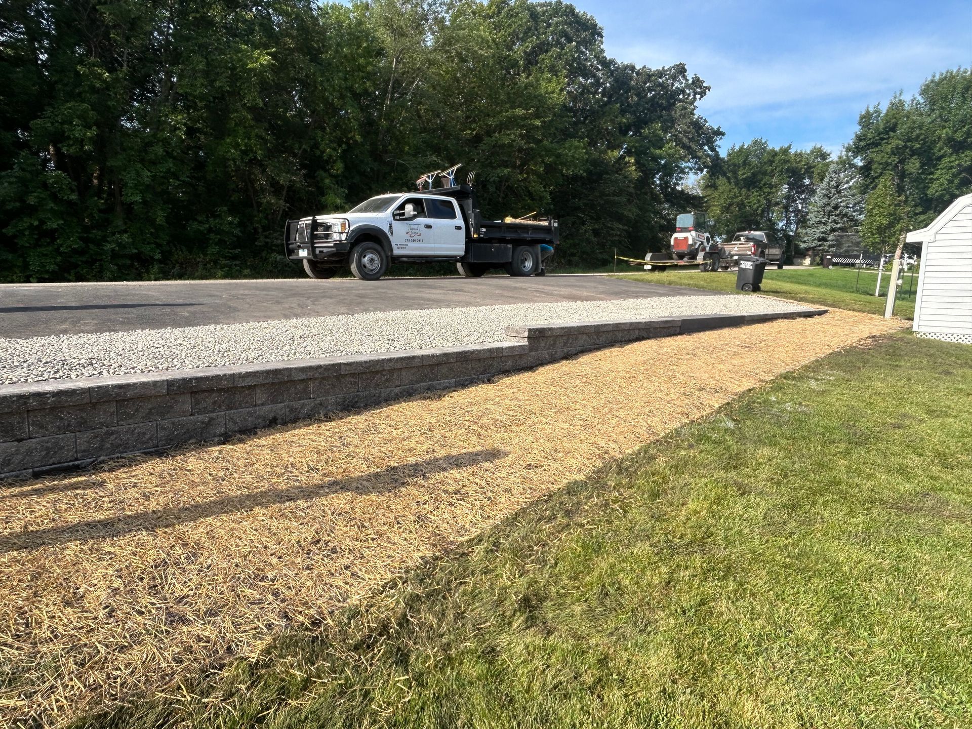 A white truck is parked on the side of the road next to a gravel road.