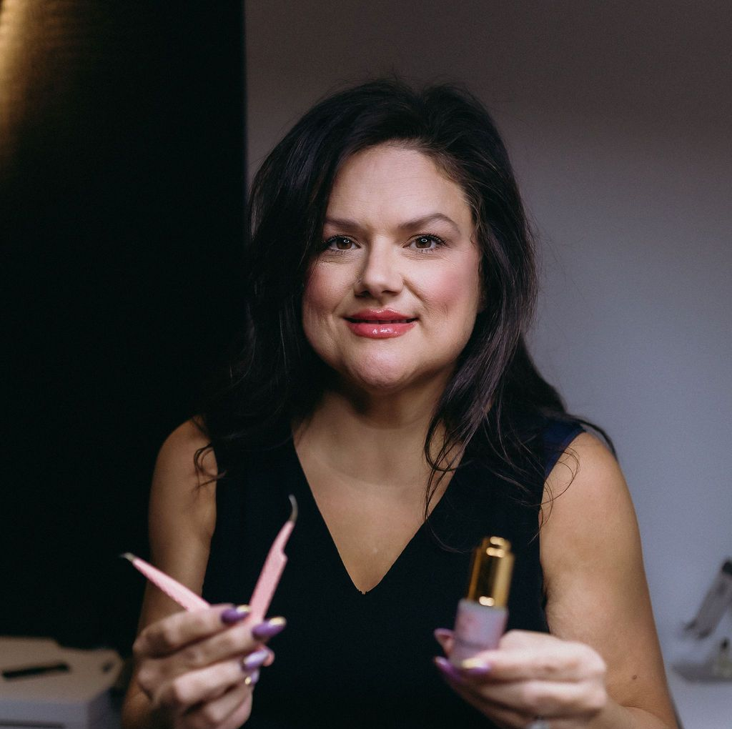A woman in a pink shirt is sitting on a couch.