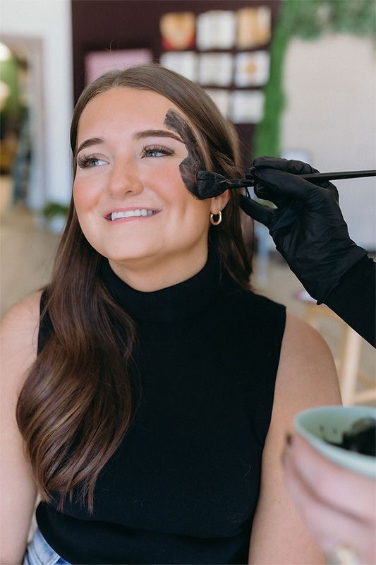 Four women are posing for a picture while sitting on a couch.