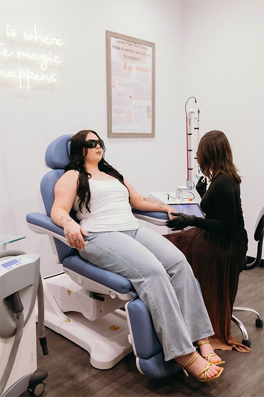 Four women are posing for a picture while sitting on a couch.