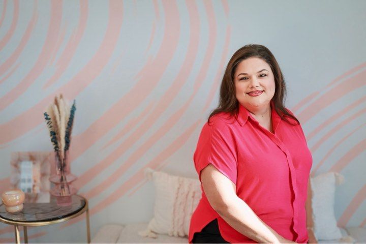 A woman in a pink shirt is sitting on a couch.