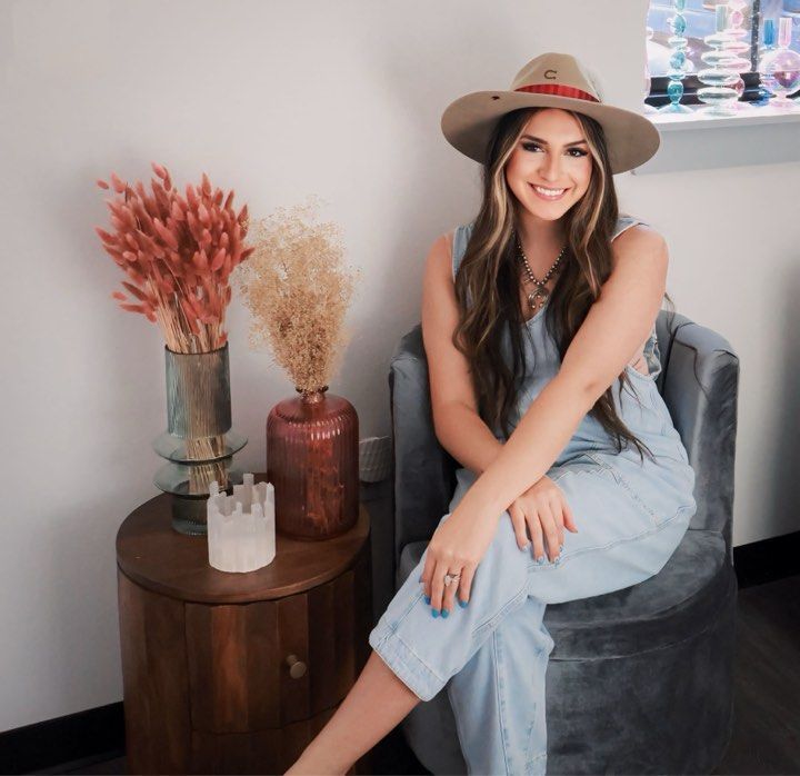 A woman wearing a hat is sitting in a chair