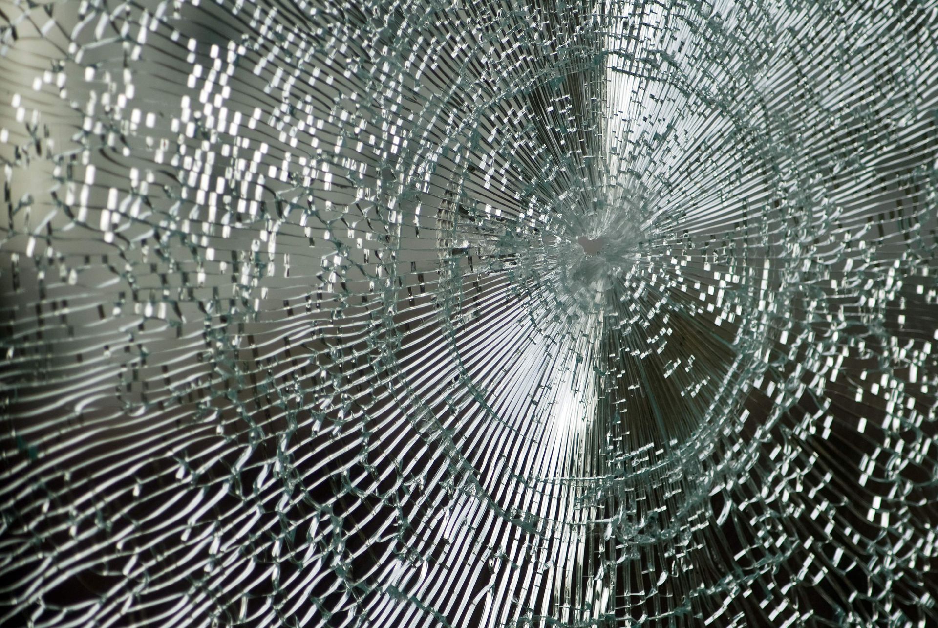 Shattered glass pane with radial cracks emanating from the point of impact.